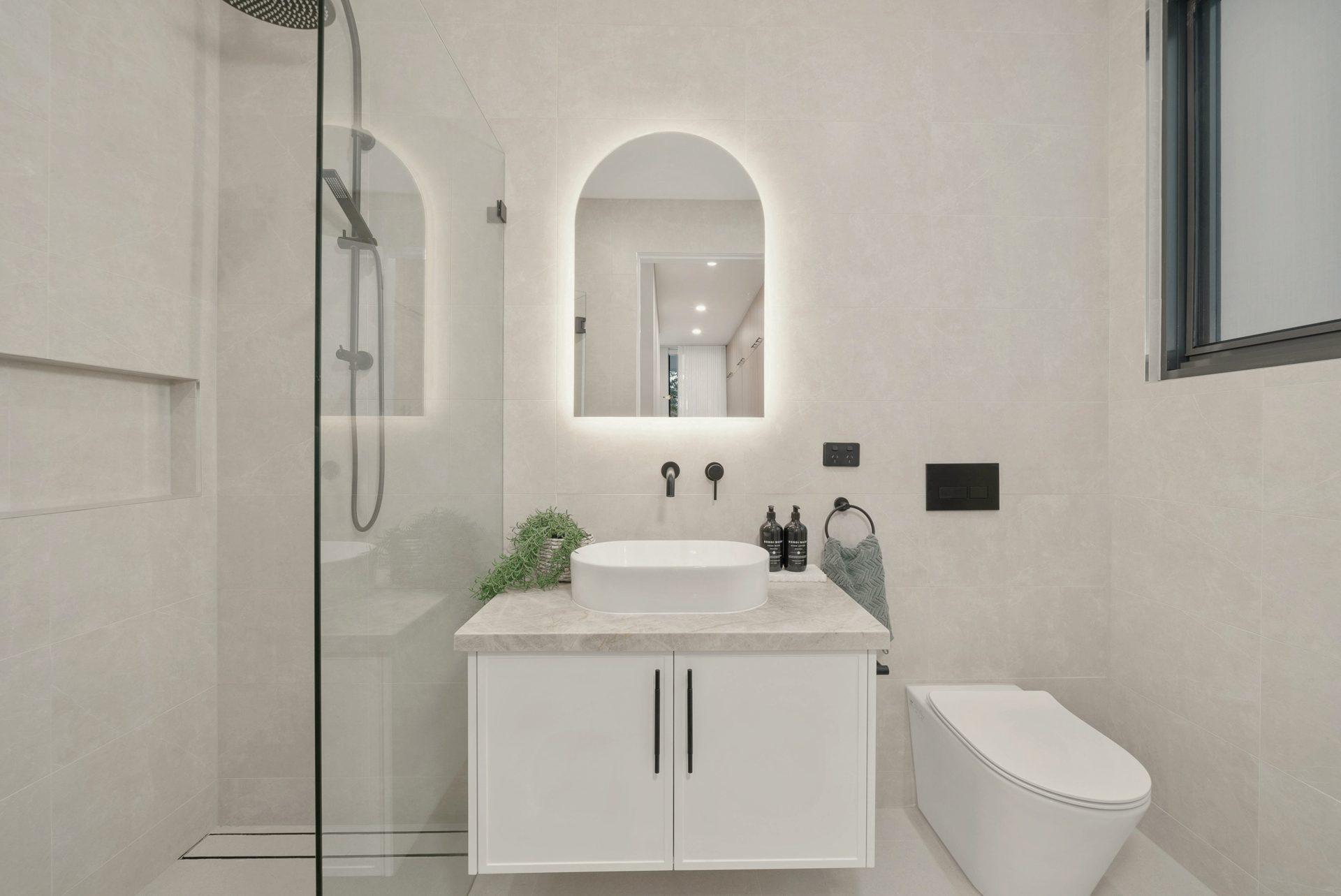Oz Builders Depot premium bathroom — light stone, matte black fittings and warm timber
